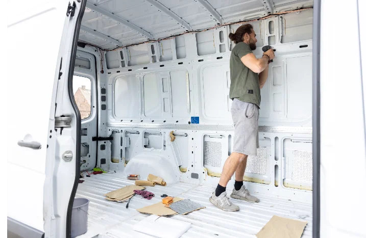 Person beim Innenausbau eines Lieferwagens mit Akkuschrauber